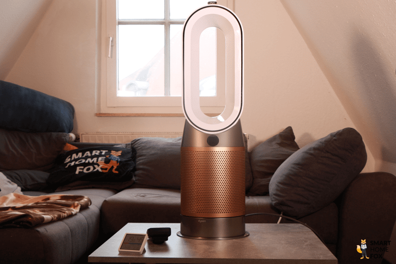 Der Dyson Purifier Hot+Cool Formaldehyde HP09 Heizlüfter und Luftreiniger steht im Test auf einem Tisch vor einer Couch.